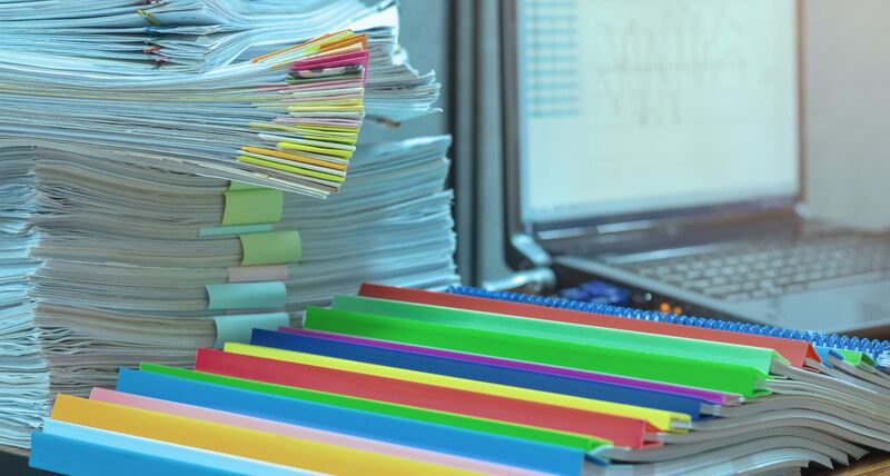 笔记本电脑旁边有成堆的纸。